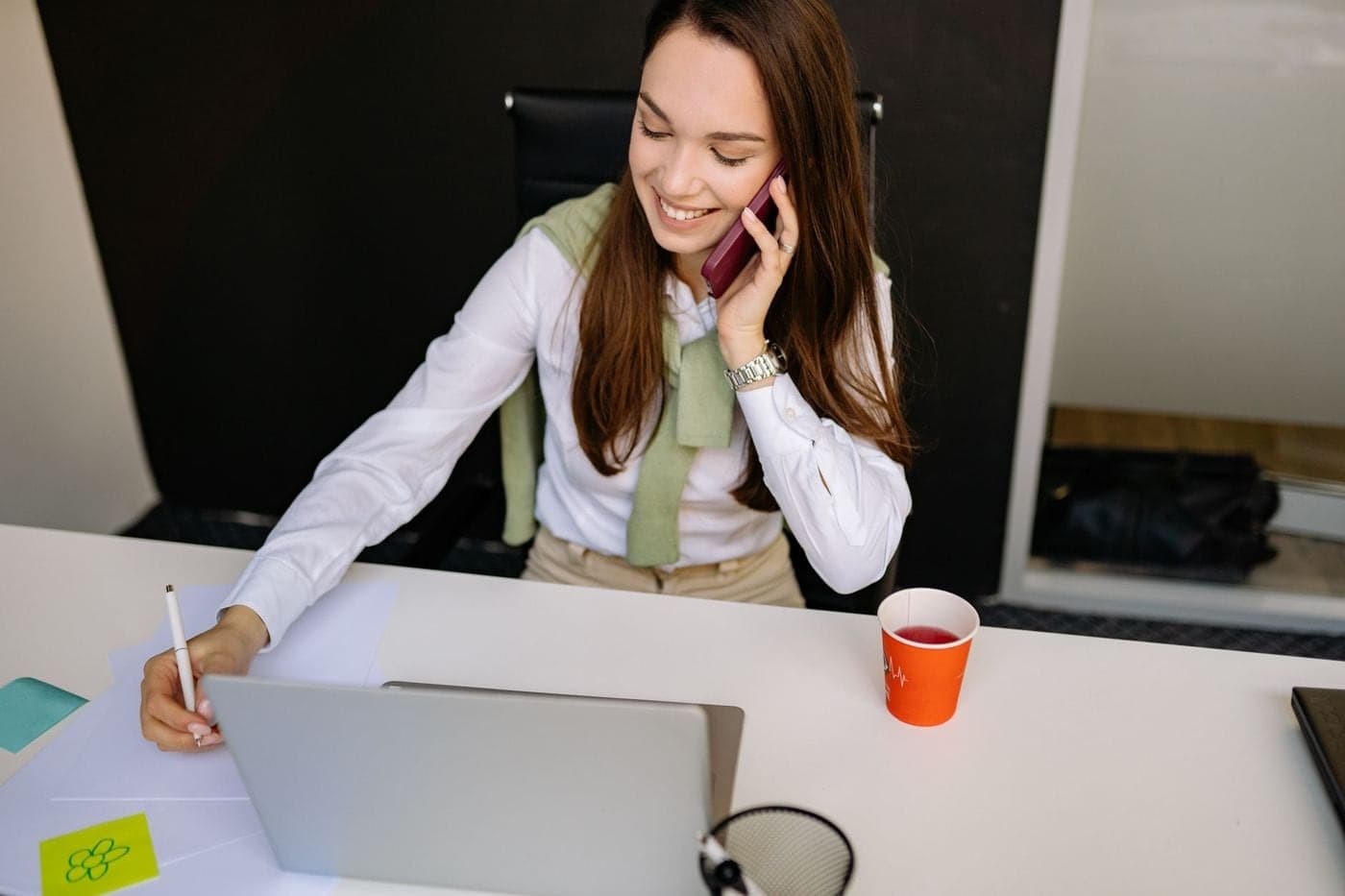 Agente de viagem falando ao telefone com o notebook aberto
